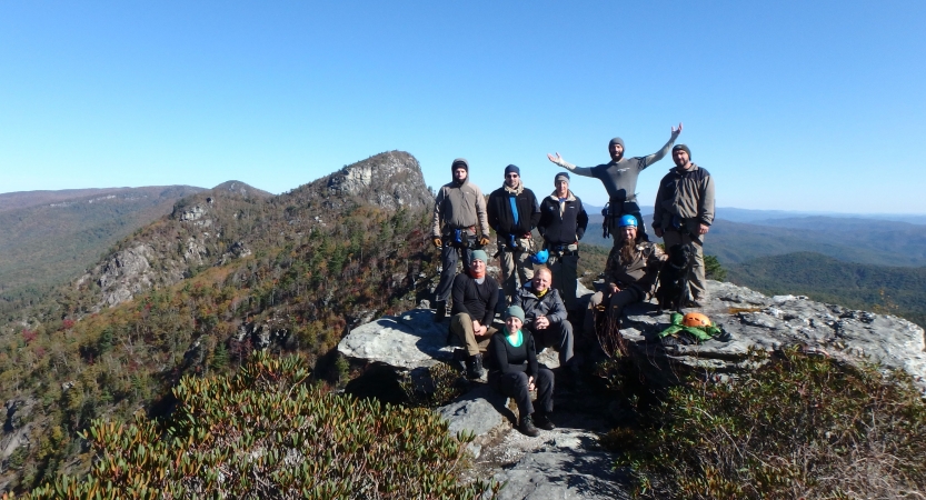 A group of people smile on a mountain summit. 